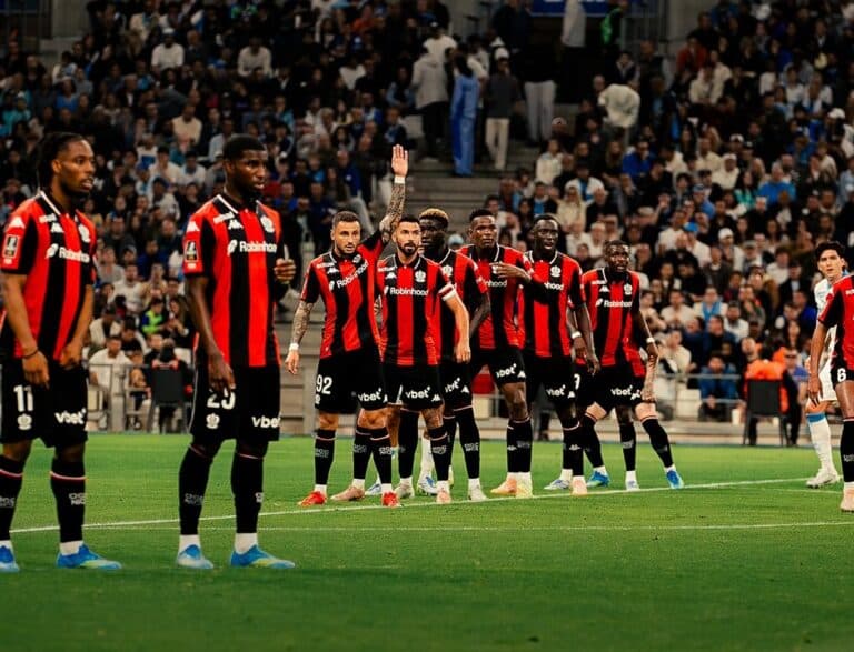 Les joueurs de l'OGC Nice avec leur maillot rouge et noir sur la pelouse prêt à défendre.