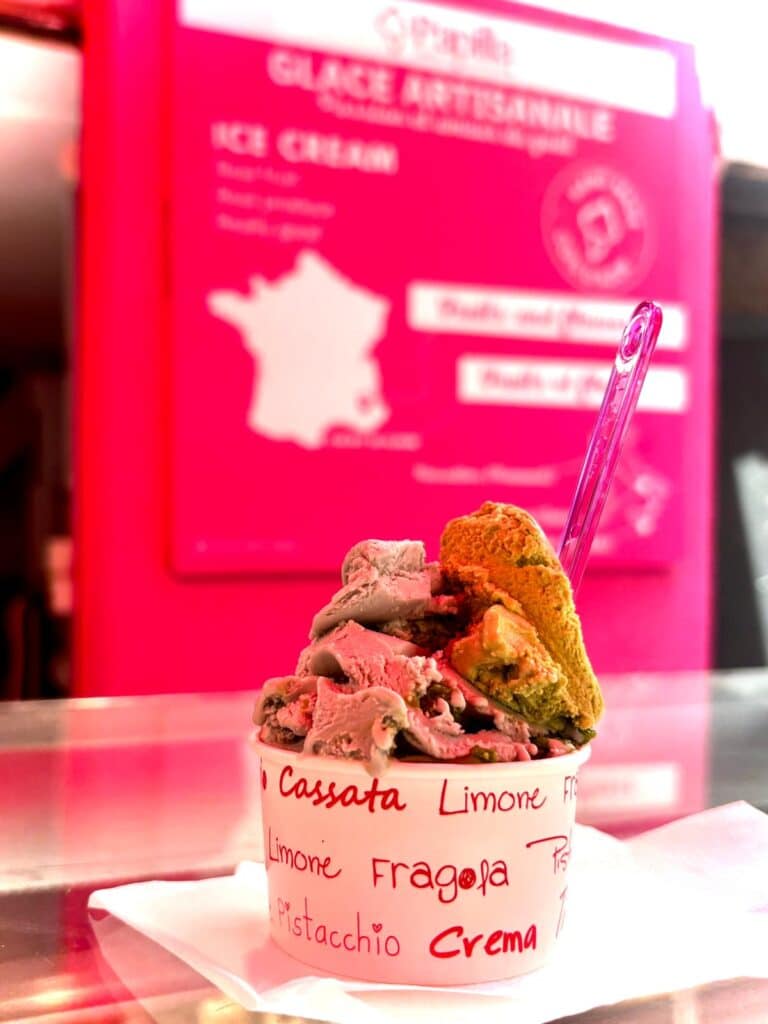 Une glace dans un pot en carton avec des toping.