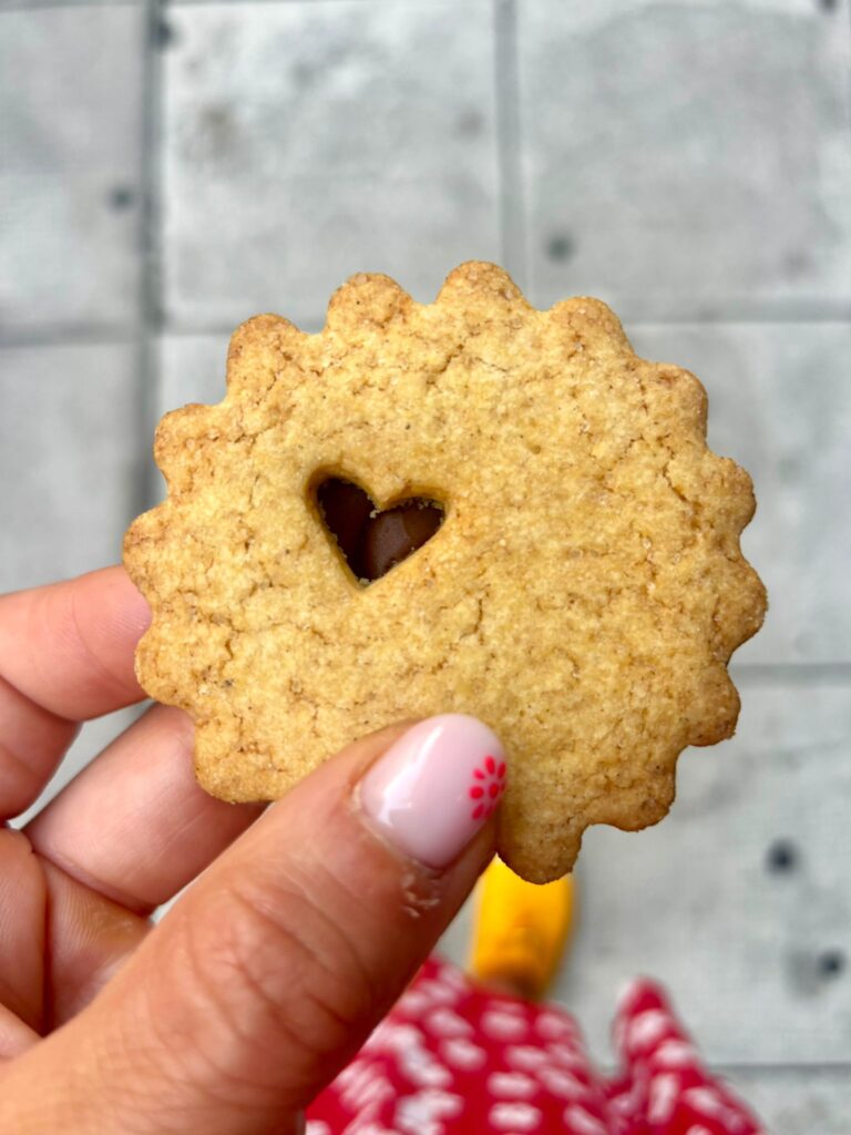 Un biscuit en étoile à plusieurs branches et un trou en cour au milieu qui montre du chocolat en dessous.