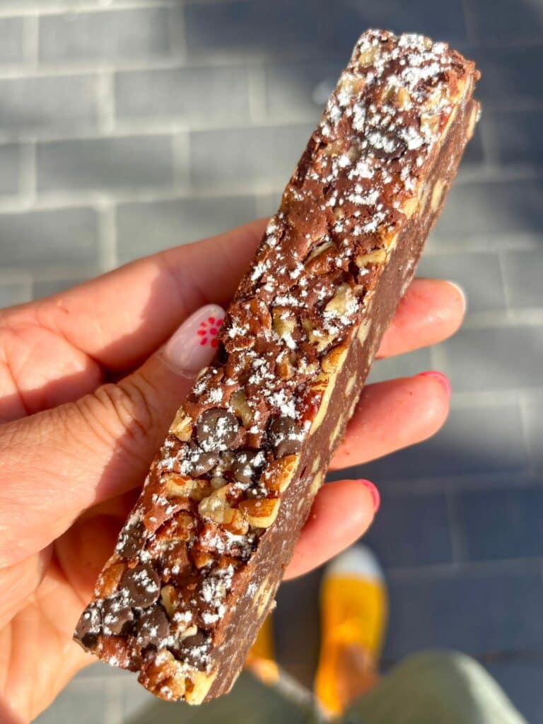 Un long gâteau fin avec des noix dessus.