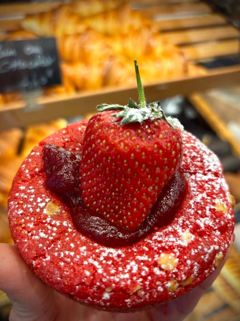 Un cookie rose avec une gelée rose et une grosse fraise au centre.