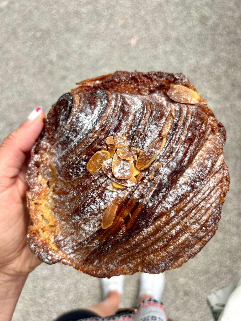 Une brioche bien cuite avec des amandes et une poudre blanche sur le dessus.