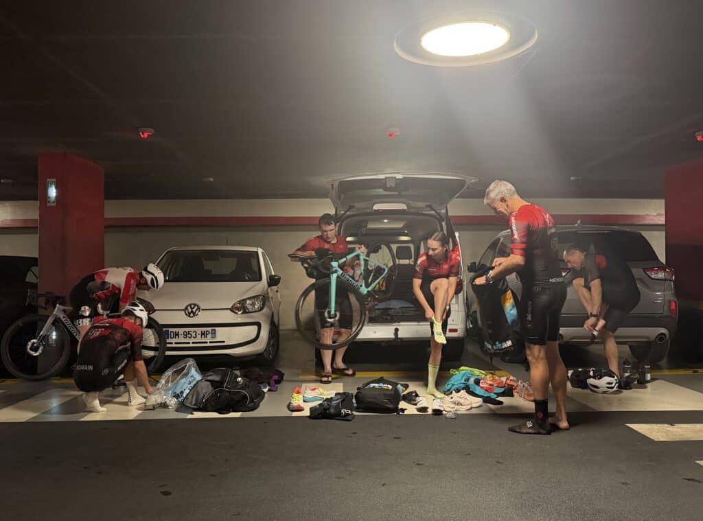 Les athlètes déchargent leurs vélos dans un parking.