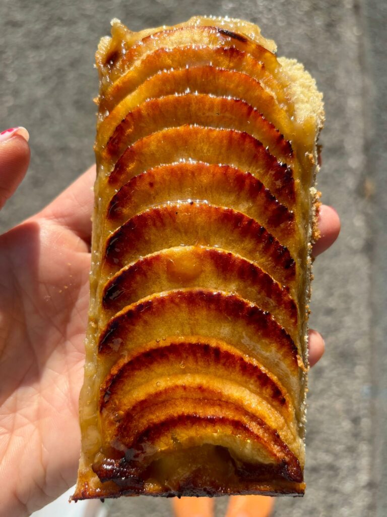 une tarte avec des pommes coupées en tranches fines sur le dessus et caramélisées.