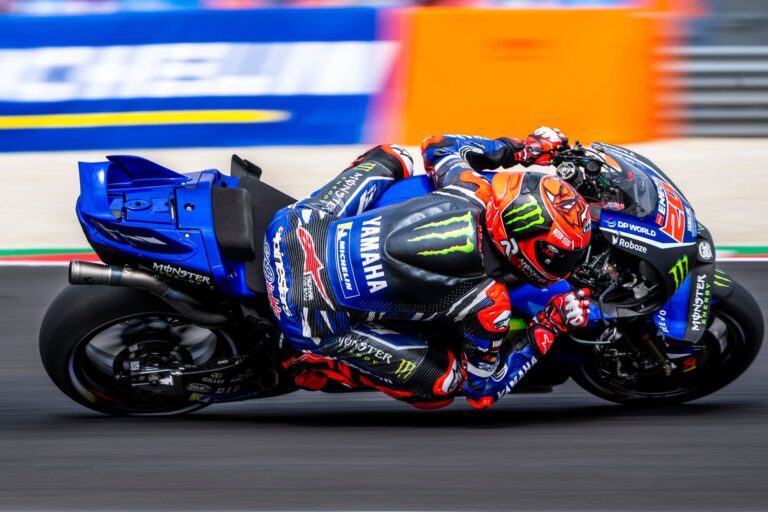 Le pilote Niçois Fabio Quartararo en plein virage avec le genou qui touche le sol sur sa moto bleu.