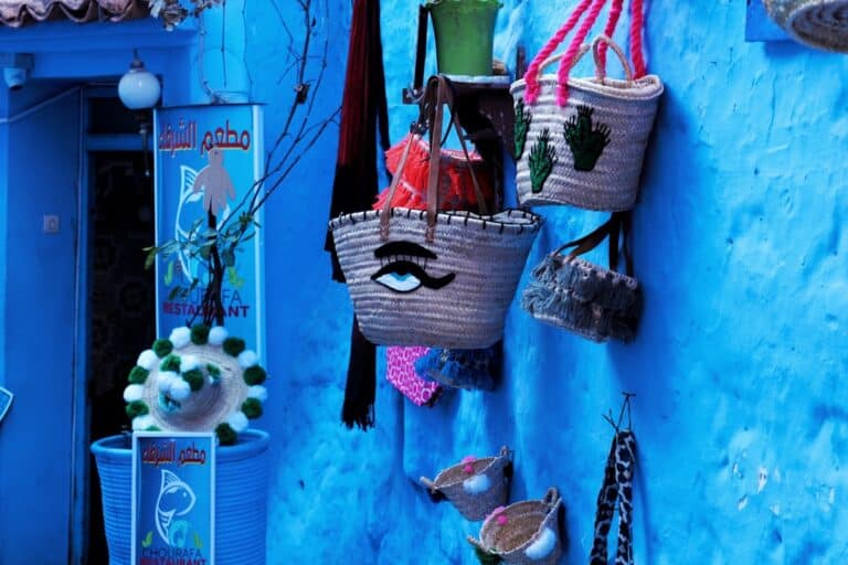 Woven bags and decorative items hang on a blue wall.