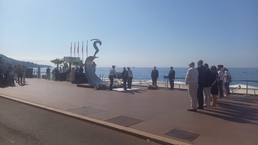 La statue du 14 juillet sur la Promenade des Anglais sur une vague en métal avec un personnage fin sur le dessus. les élus sont devant.