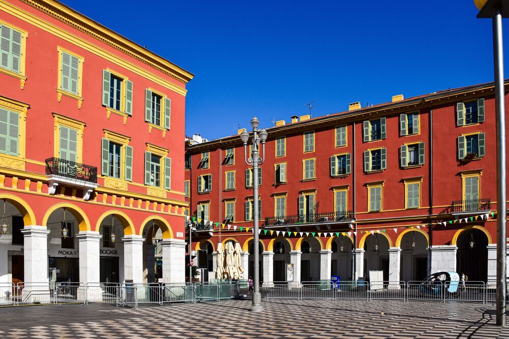 La place Masséna avec ses façades rouges et son sol en damier noir et blanc.