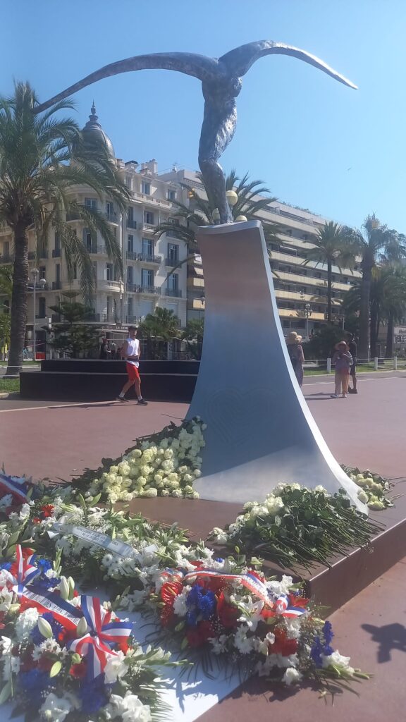La statue du 14 juillet sur la Promenade des Anglais sur une vague en métal avec un personnage fin sur le dessus.