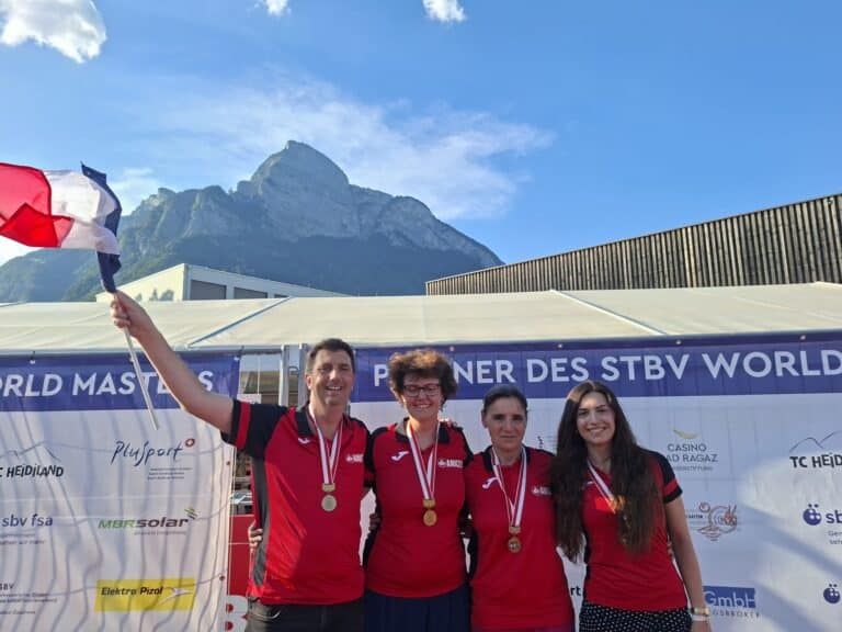 L'équipe Niçoise de Torball sur le podium avec leurs tenues rouge et noir, drapeau français à la main et un paysage montagneux en arrière plan.