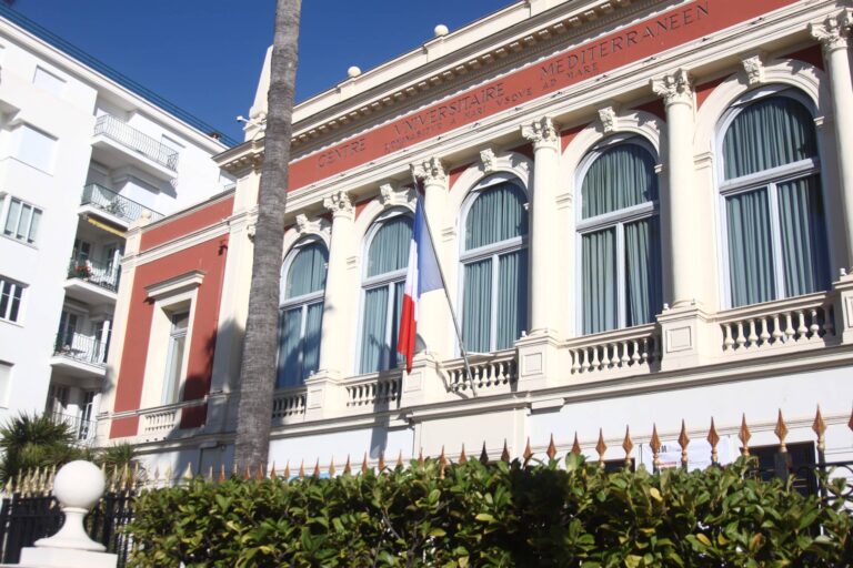 Le centre universitaire méditerranéen avec sa façade rouge et ses grandes fenêtres arrondies.