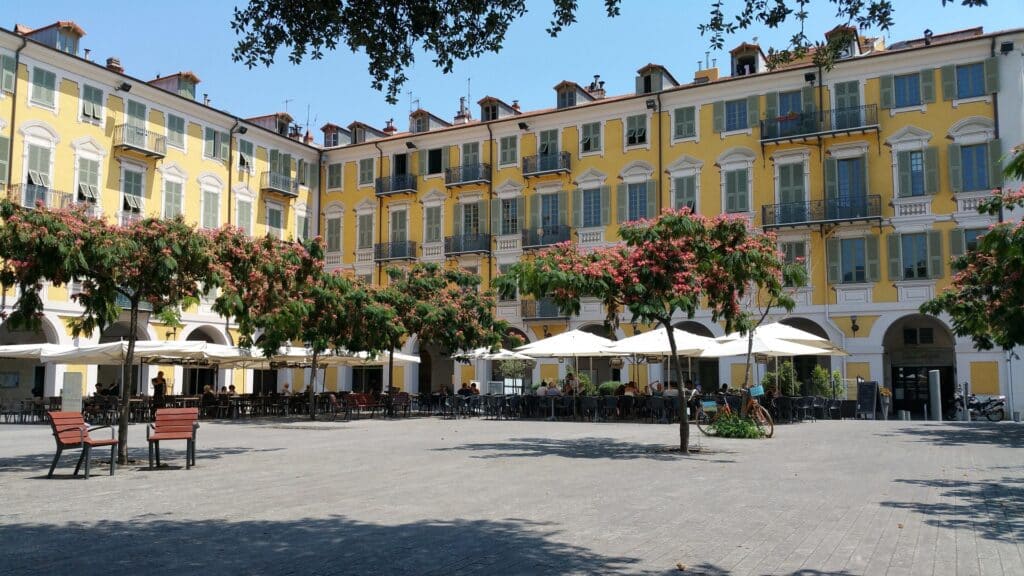 La place Garibaldi de Nice avec ses immeubles jaunes et ses terrasses de café.