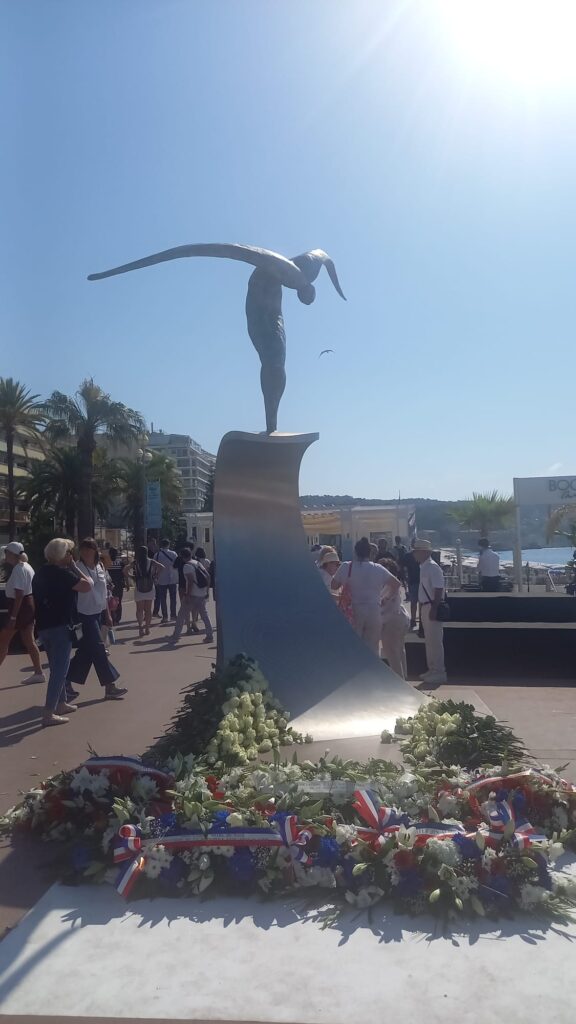 La statue du 14 juillet sur la Promenade des Anglais sur une vague en métal avec un personnage fin sur le dessus.