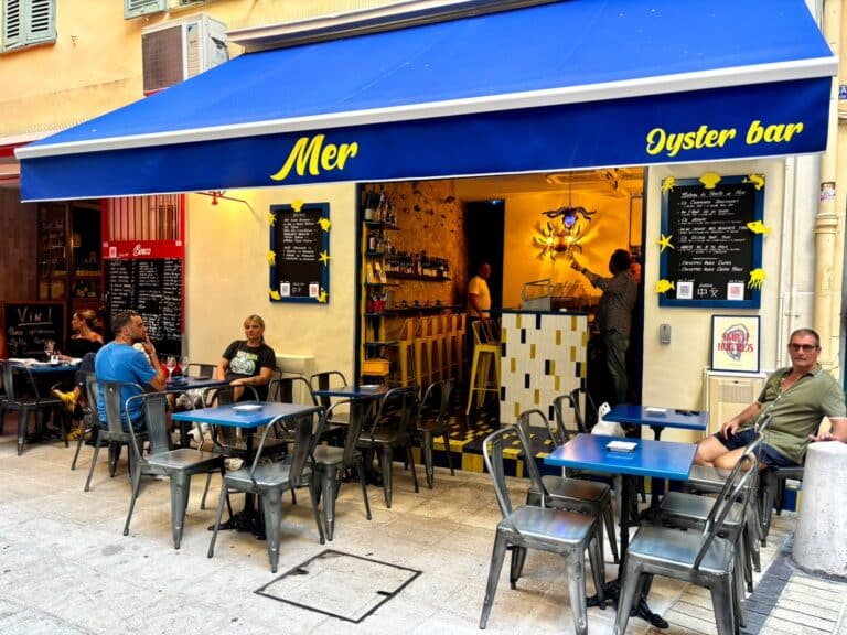 La devanture du restaurant Mer avec un haut-vent bleu, des tables devant le restaurant.