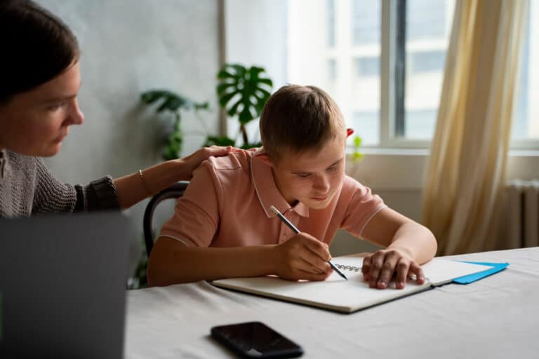 Une AESH aide un enfant atteint d'autisme pour l'aider à faire ses devoirs en toute bienveillance.