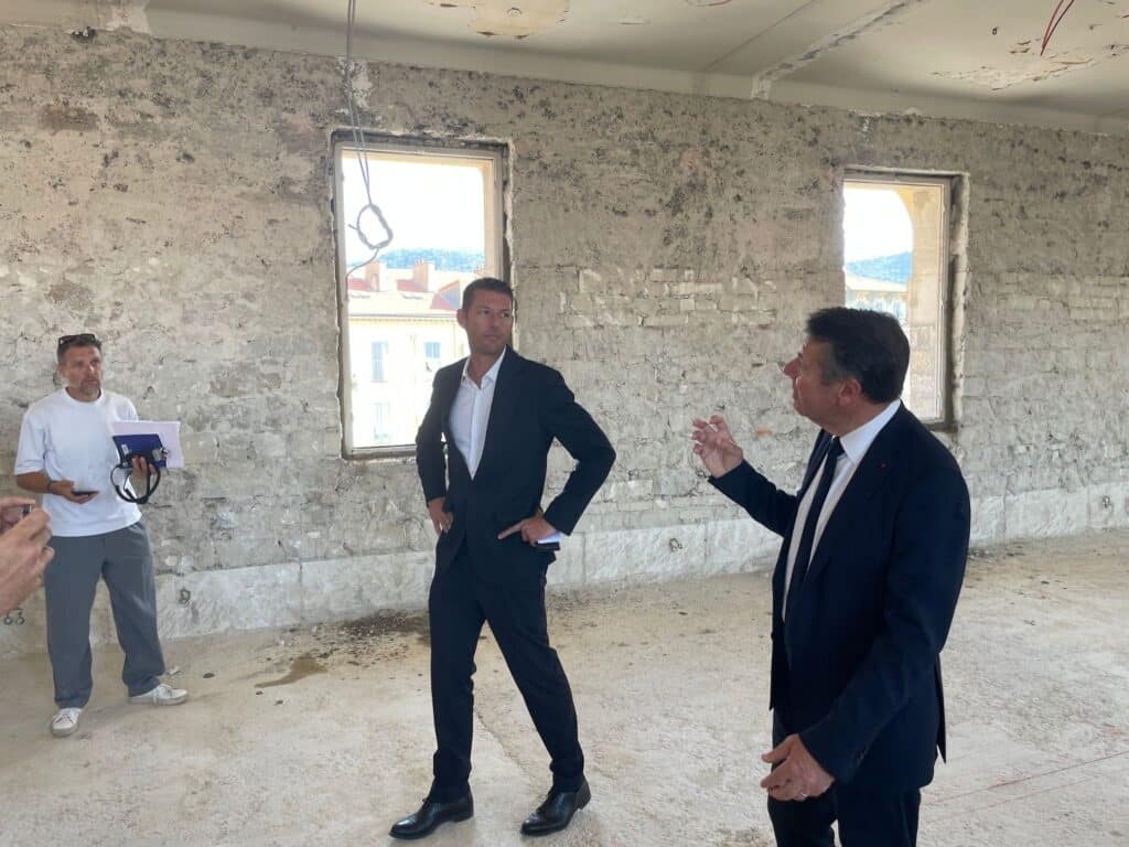 Christian Estrosi debout en costume au milieu du chantier de construction du nouvel internat du Lycée Masséna