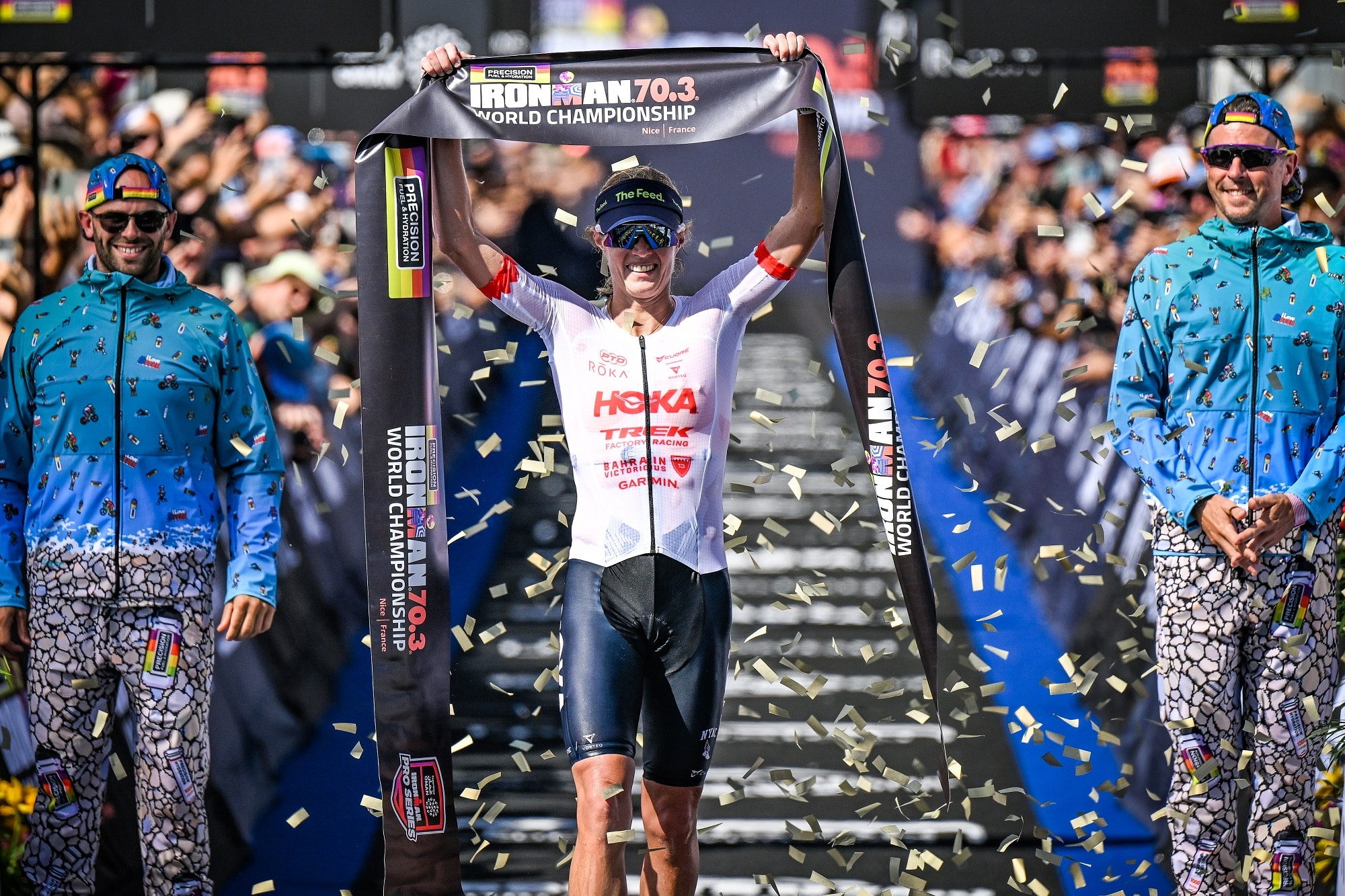 La vainqueur de l'édition 2026 du championnat du monde d'Ironman 2026 Taylor Knibb lève bras avec la banderole symbolisant l'arrivée dans les mains.