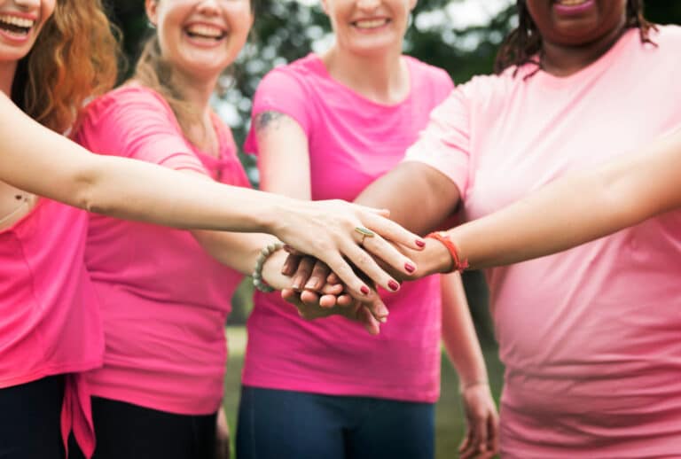 Des femmes se tiennent la main en arc de cercle habillées de rose.