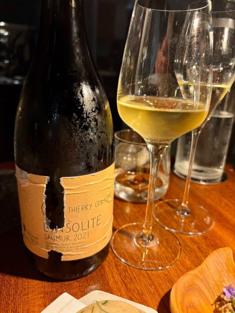 Une bouteille et un verre de vin blanc.