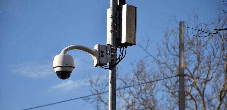 Une caméra de vidéo surveillance ronde accrochée à un poteau.
